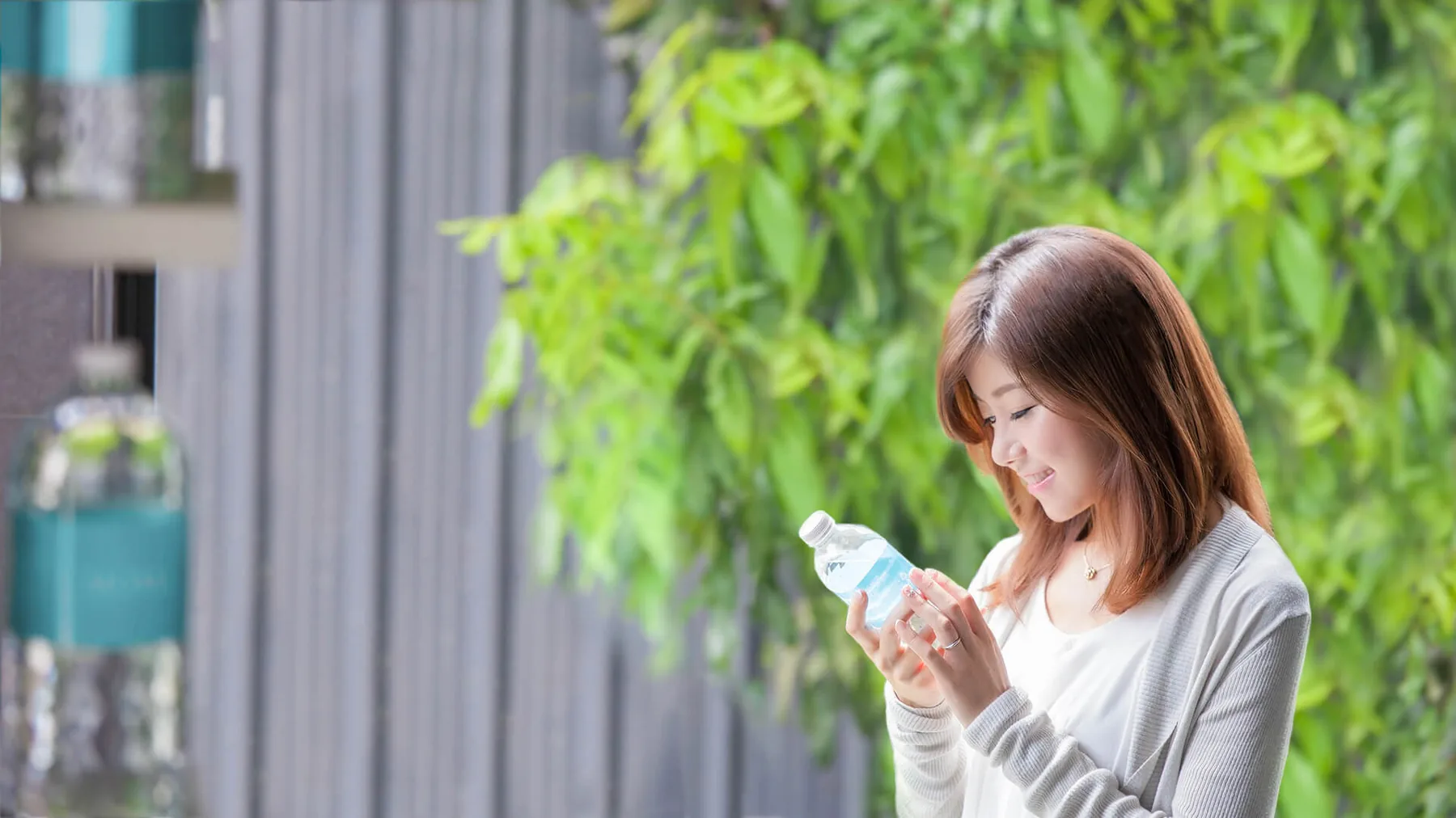 Yumi reading a MOMAwater label among greenery — a moment of clarity.