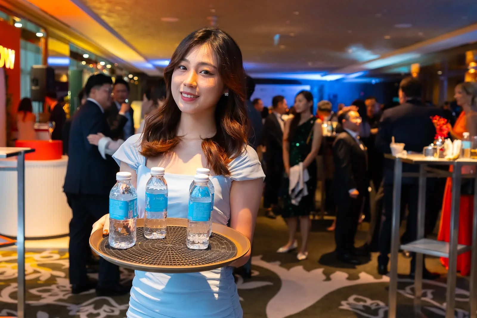 A host presenting MOMAwater on a tray at the Michelin Guide event.