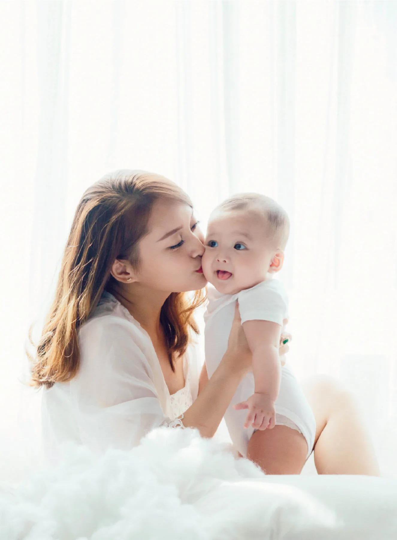 A mother kissing her baby in soft light — safe, even for new mothers and babies.
