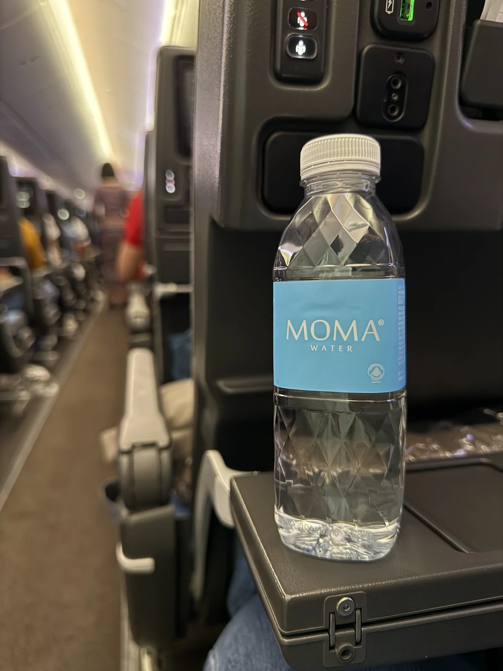 A MOMAwater bottle standing at the seat aboard a Singapore Airlines flight.