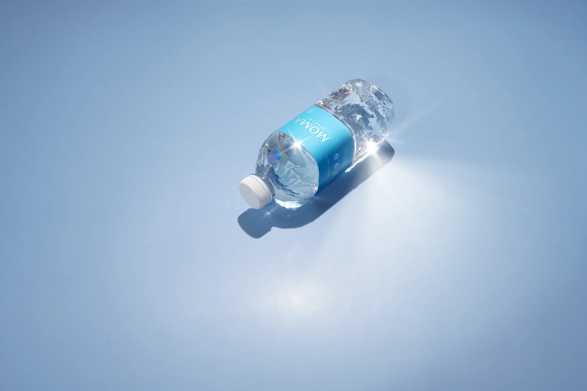 MOMAwater bottle on a blue gradient with a sparkle of light.